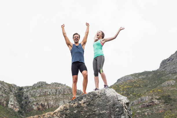 istock Excited young couple on rock against sky 674457142