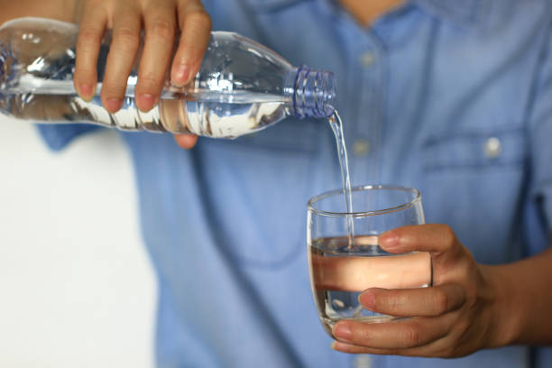 istock Woman pouring water from a plastic bottle into a glass 674457580