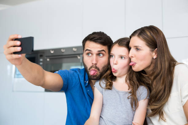 istock Family sticking out tongue while clicking selfie 674462990
