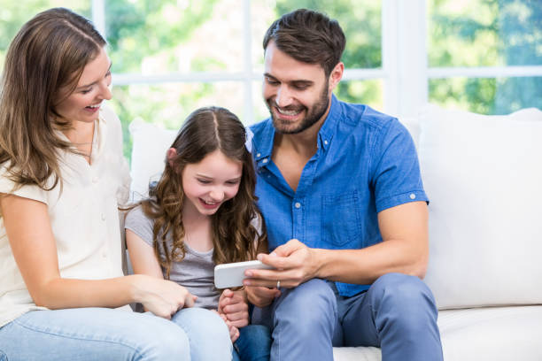 istock Family looking at smart phone while sitting on sofa 674463636