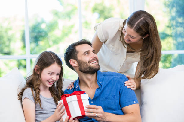 istock Man looking at wife while holding gift with daughter 674463808