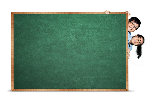 Image of primary students hiding behind blank chalkboard, isolated on white background