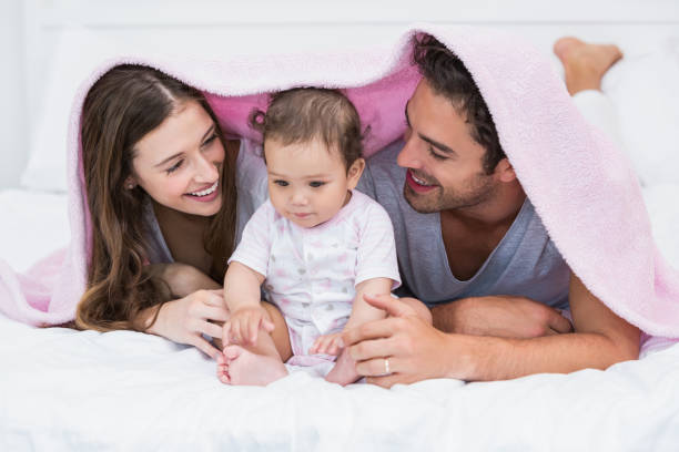 istock Couple enjoying with baby under blanket on bed 674473750