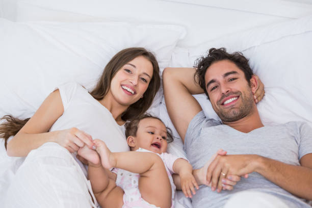 istock High angle view of couple lying on bed with baby 674473840