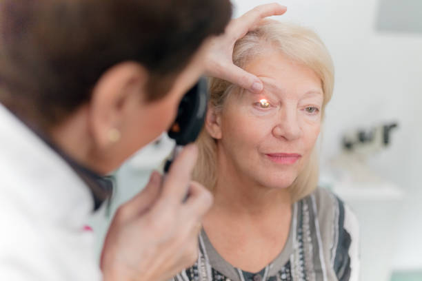 optician mirando a los ojos de los pacientes - ophthalmic fotografías e imágenes de stock