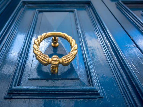 Antique gold or brass door knocker on a blue painted door. Old townhouse in Sliema, Malta. stock photo