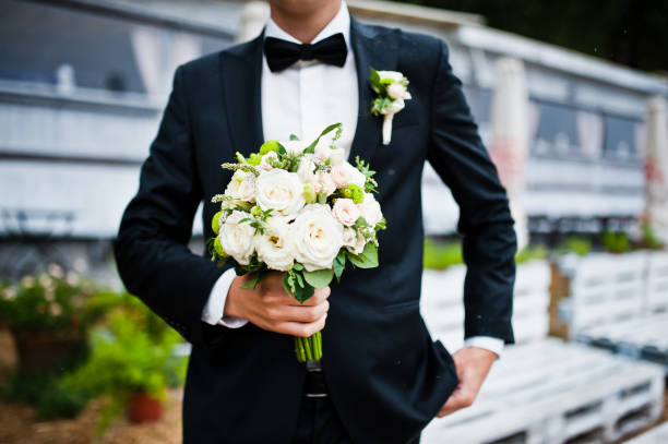 istock Wedding bouquet at hand of groom with bow tie 674501394