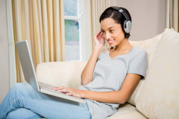 istock Smiling brunette using laptop and headphones 674522520