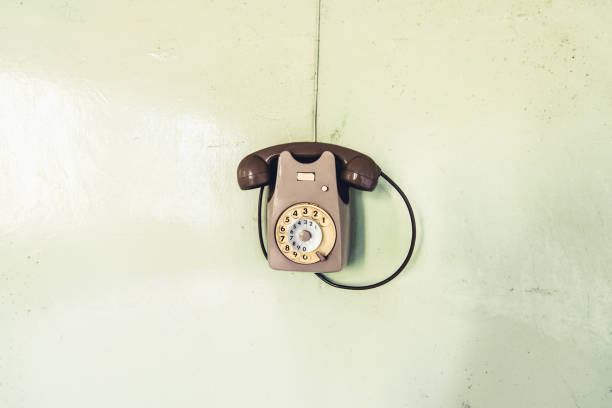 Close up of black obsolete rotary payphone on red wood background.