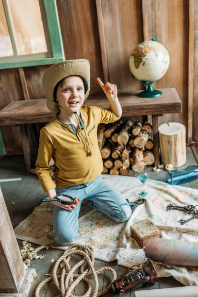 istock Smiling little boy in hat holding magnifier and pointing up with finger 674529278