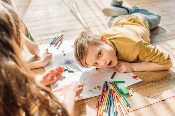 istock cute kids drawing on paper with pencils while lying on floor 674529622
