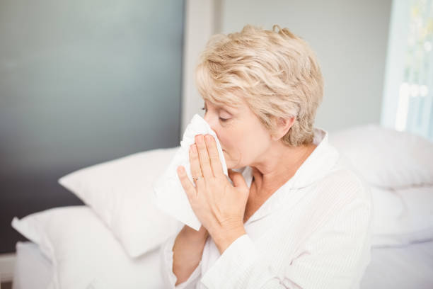 mulher sênior, cobrindo o nariz enquanto espirros em casa - human parainfluenza virus - fotografias e filmes do acervo