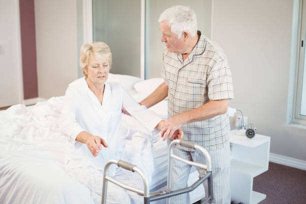 istock Senior man assisting ill woman in getting up from bed 674534892