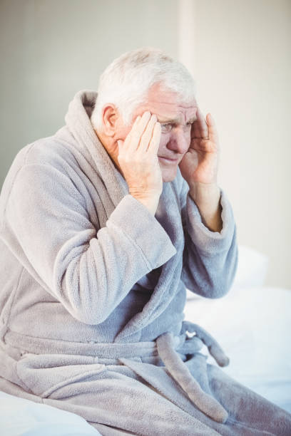 istock Senior man suffering from headache while sitting on bed 674535380