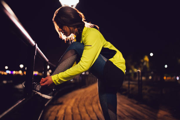 istock Woman runner tying her shoelaces on a pier at night 674554740