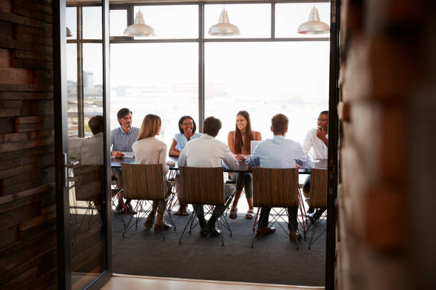 istock Team in a boardroom meeting seen through open doors, full length 674555268
