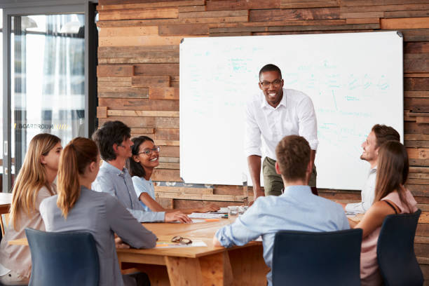 istock Young black man stands addressing colleagues at a meeting 674555314