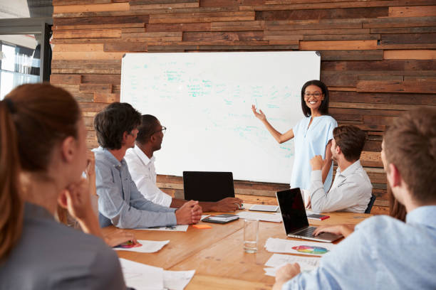 istock Young black woman giving business presentation at whiteboard 674555332