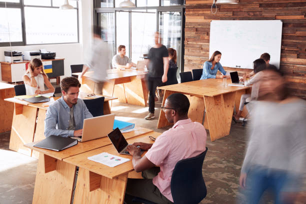 istock Young adult colleagues working in a busy office, motion blur 674555342