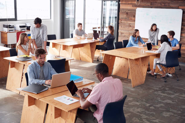 istock Young adult colleagues working in busy office, elevated view 674555362