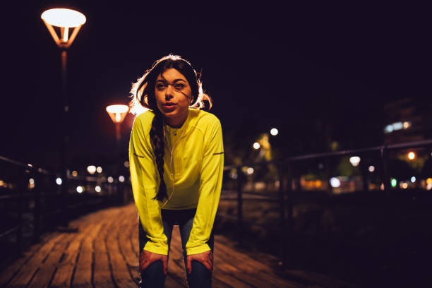 istock Young woman taking a break after night jogging on pier 674555720