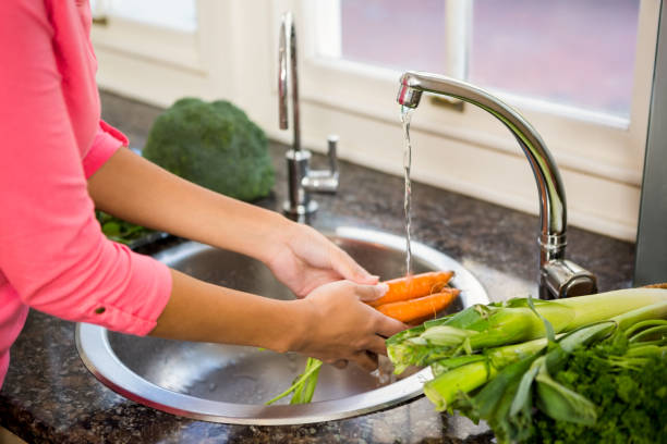 istock Mid section of woman washing carrots 674559486