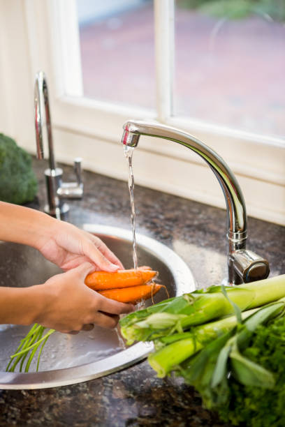 istock Mid section of woman washing carrots 674559502