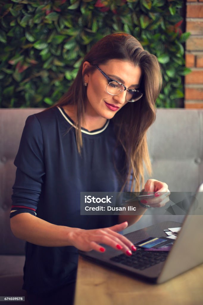 Business woman working on laptop and using credi card Young cute woman using laptop in a coffee house Adult Stock Photo