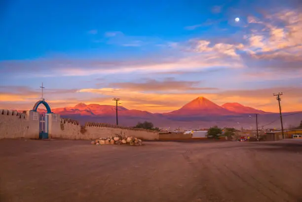 Andes and the desert with Licancabur volcano on the Bolivian border in the sunset at full moon, San Pedro de Atacama, Chile, South America