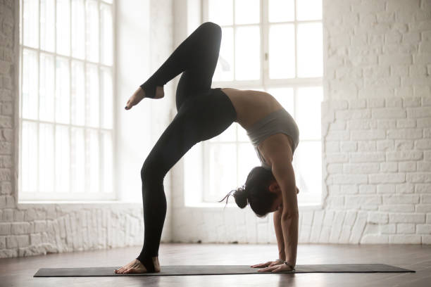 istock Young attractive woman in One legged Wheel pose, white studio 674564288
