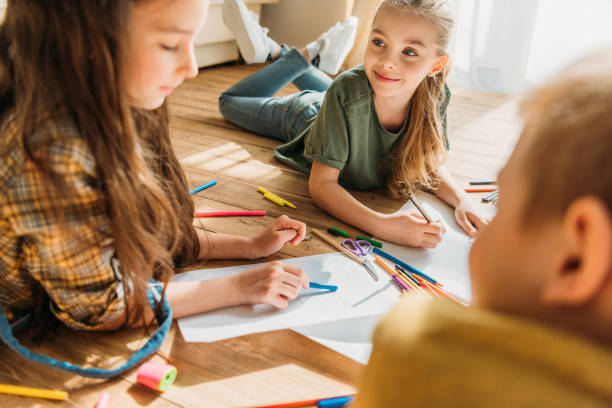 istock cute kids drawing on paper with pencils while lying on floor 674564810