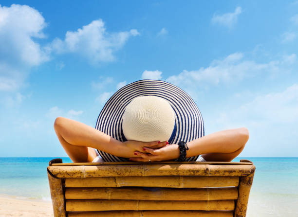 woman in hat relaxing on beach, looking at sea. copy space. - sunbed imagens e fotografias de stock