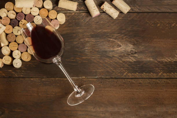 istock Glass of red wine and corks on dark background 674571126