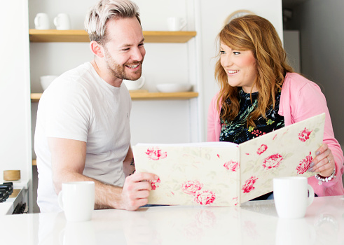 A young couple smile and laugh as they look through their wedding planner
