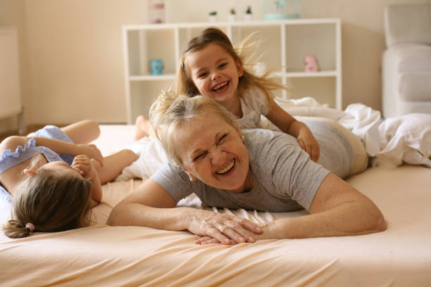 istock Grandmother playing in bed with her granddaughters. 674586306