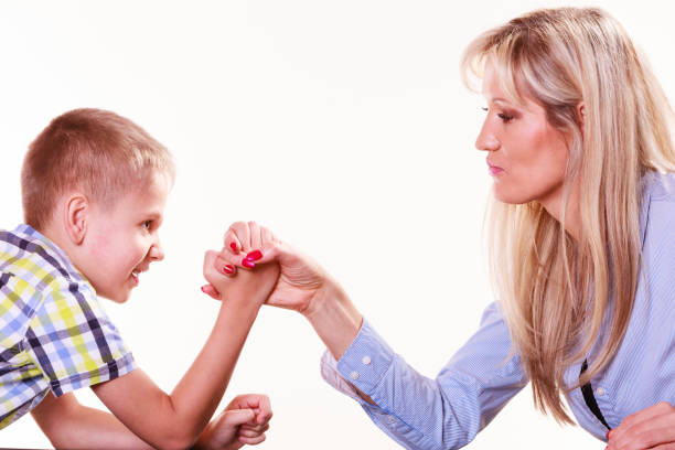istock Mother and son arm wrestle sit at table. 674591946