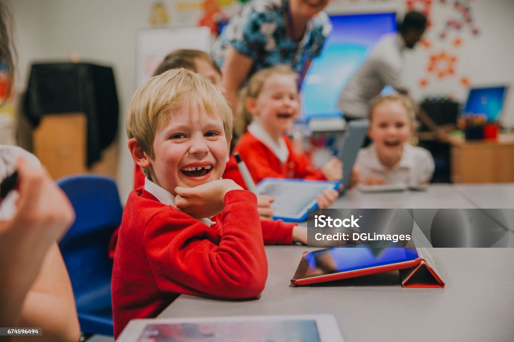 Happy Student In Technology Lesson Happy little boy is smiling for the camera while using a digital tablet in his technology lesson at school. Elementary Student Stock Photo