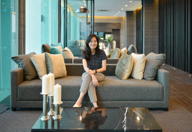 istock Asian woman smiling on sofa in luxury condo 674613164