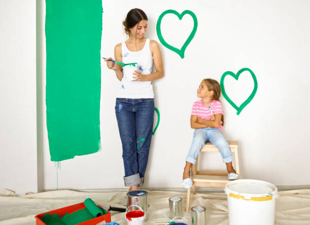 istock Mother and daughter painting wall 674621058