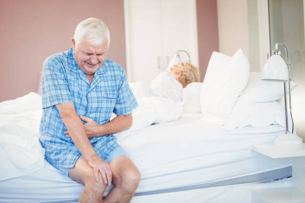 istock Suffering senior man holding his belly on bed 674627646