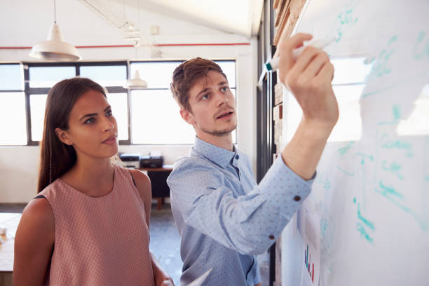 istock Young man and woman work at whiteboard in office, close up 674627734