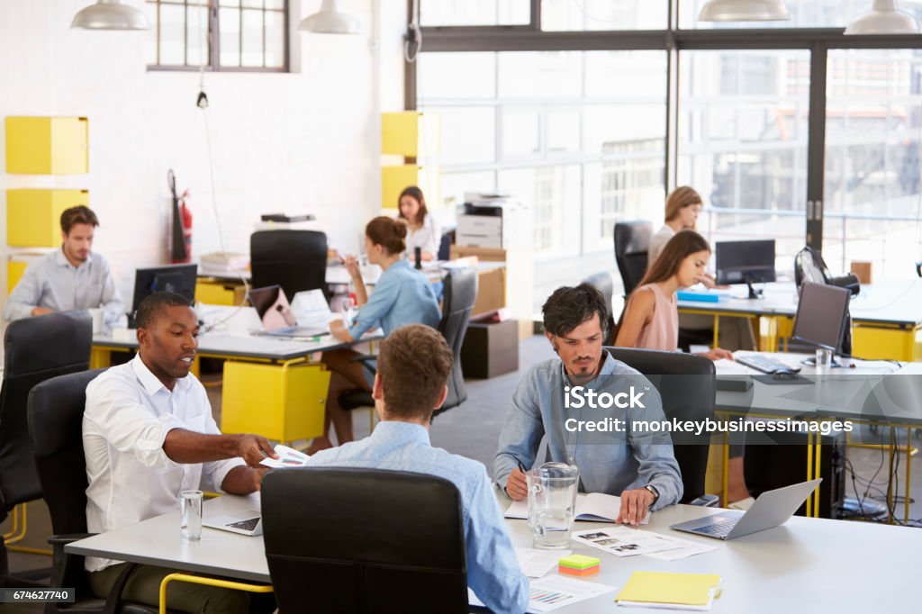 Team aziendale creativo che lavora in un affollato ufficio open plan - Foto stock royalty-free di Ufficio open space