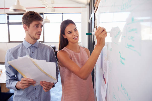 istock Young man and woman making notes on a whiteboard in office 674627818