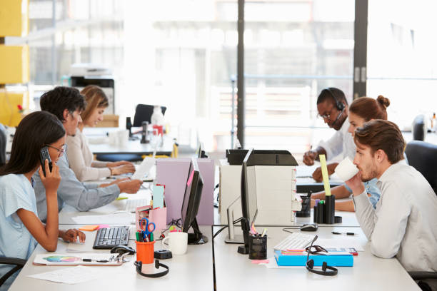 istock Young colleagues working in a busy open plan office 674627998