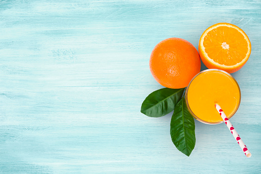 Orange juice glass and fruits on blue wooden tropical background