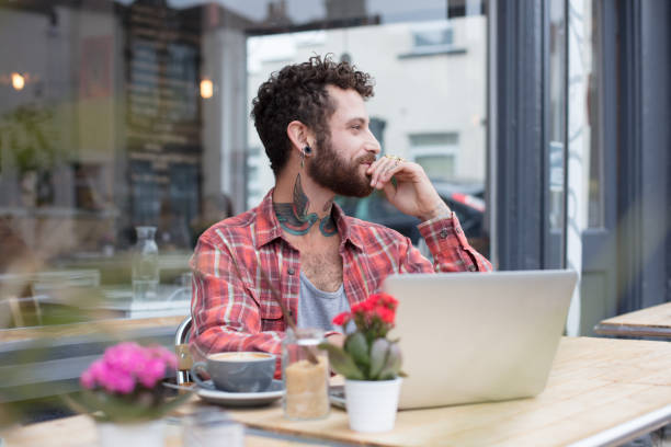 Tattooed man sat outside cafe