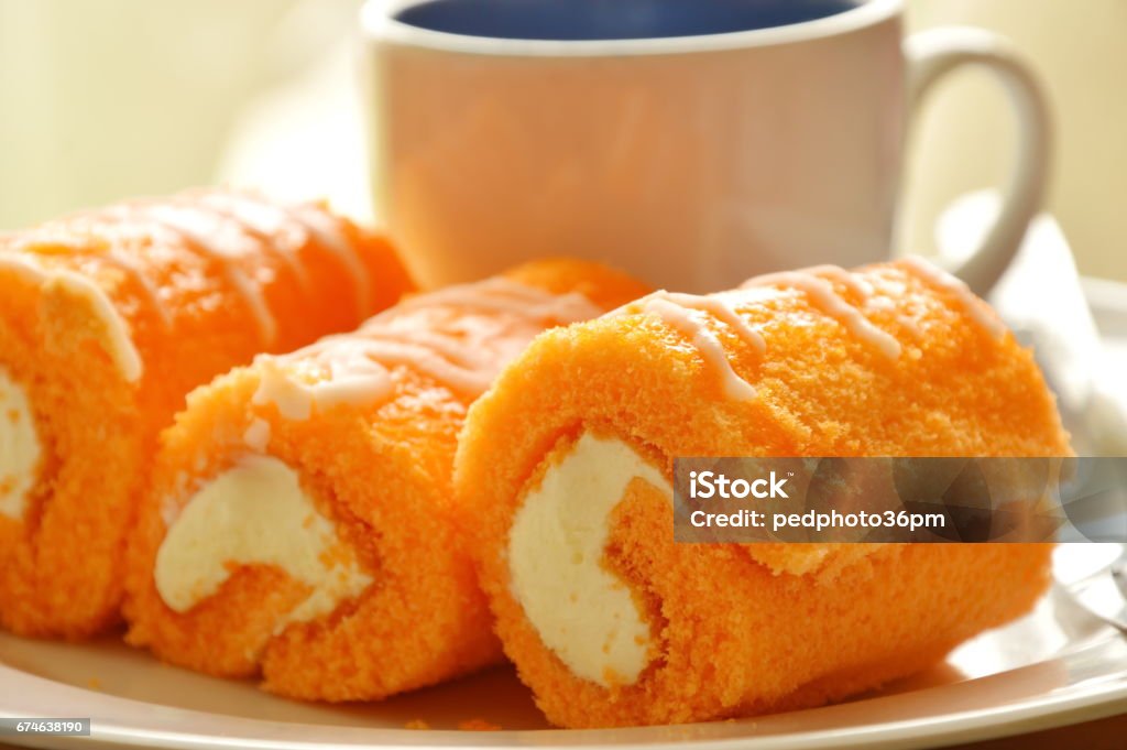 orange cake roll stuffed cream with coffee orange cake roll stuffed cream eat couple with coffee on dish Baked Stock Photo