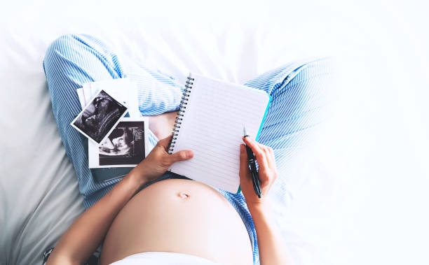 istock Pregnant woman makes notes in notebook and holding ultrasound image and medical documents 674638900