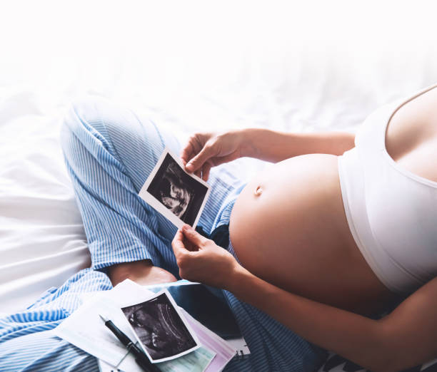 istock Pregnant woman makes notes in notebook and holding ultrasound image and medical documents 674638950