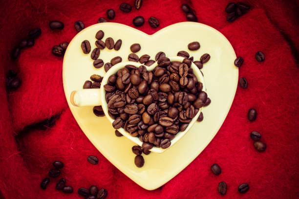 istock Heart shaped cup with coffee beans on red 674639036